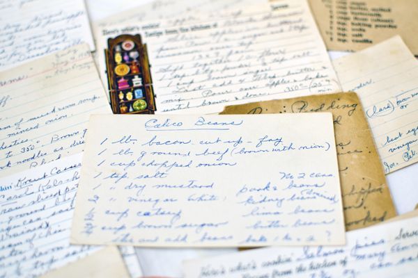 Scattered handwritten letters and notes on a tabletop, with a small colorful decorative strip.