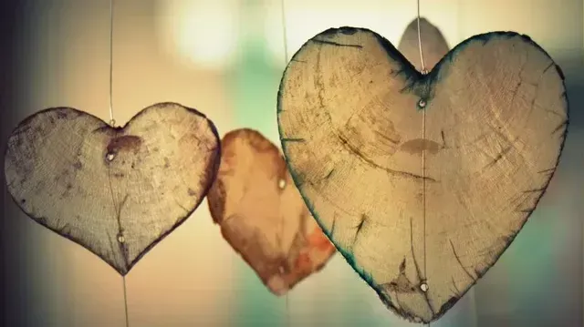 Three hanging heart ornaments in warm, vintage tones against a blurred background.