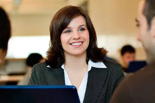 Smiling woman in a blazer talking across a table in an office