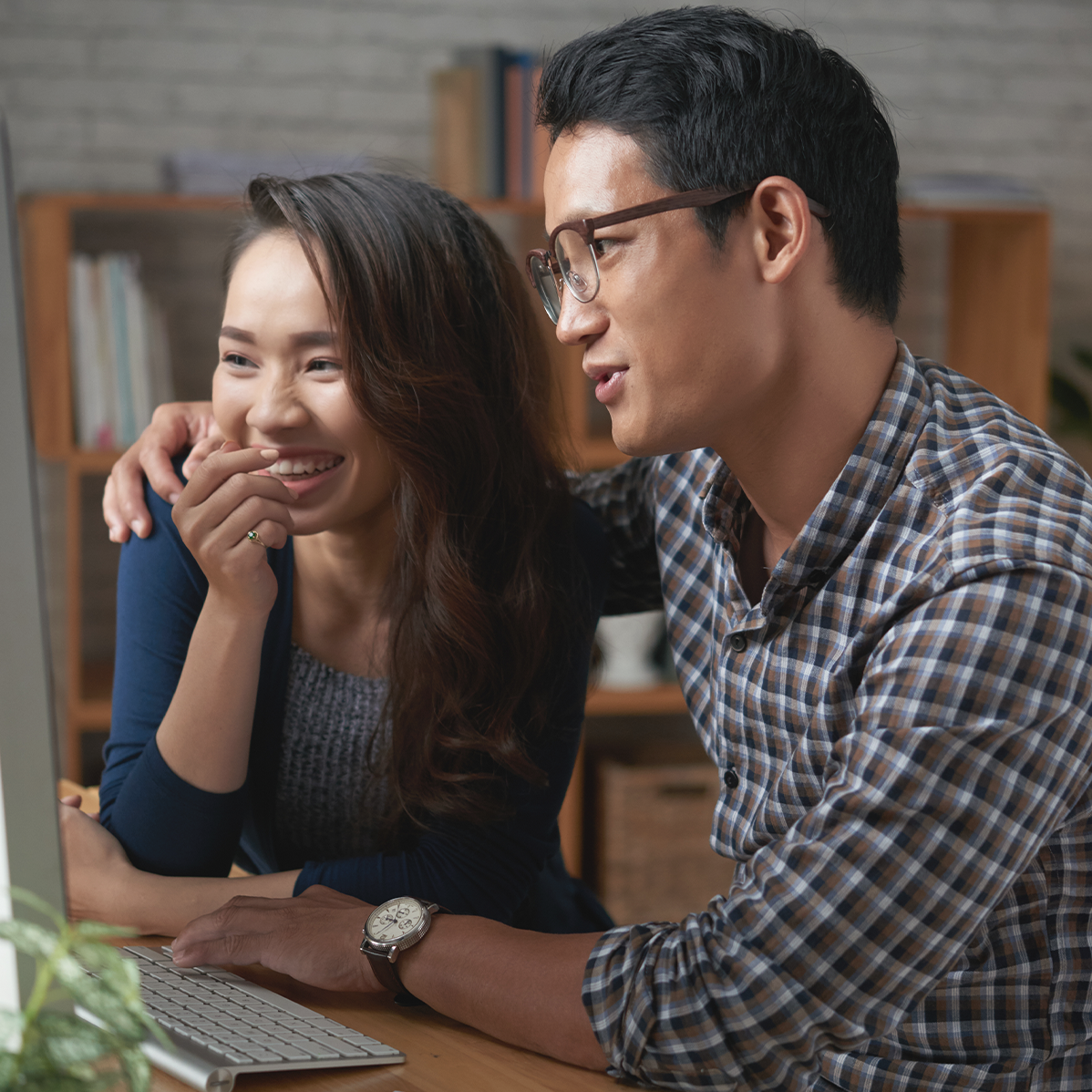 A man and a woman are looking at a computer screen together.