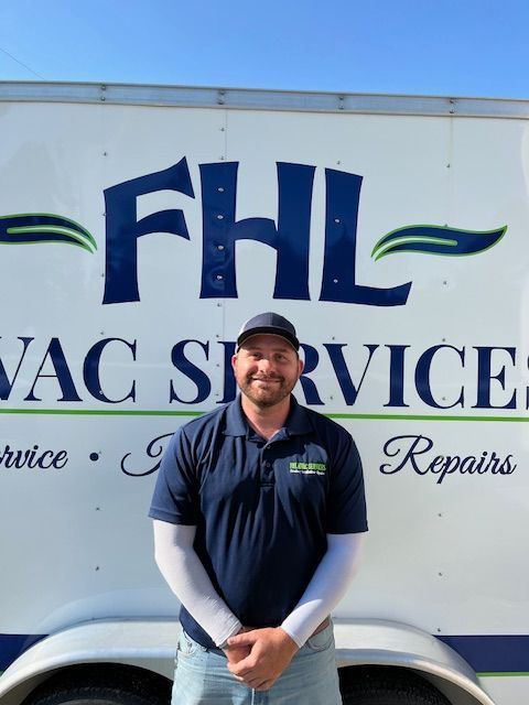 Man in blue shirt and cap stands in front of a trailer with 