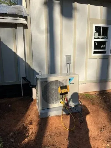 A large air conditioner is sitting outside of a building next to a window.