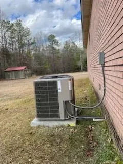 A large air conditioner is sitting on the side of a brick building.