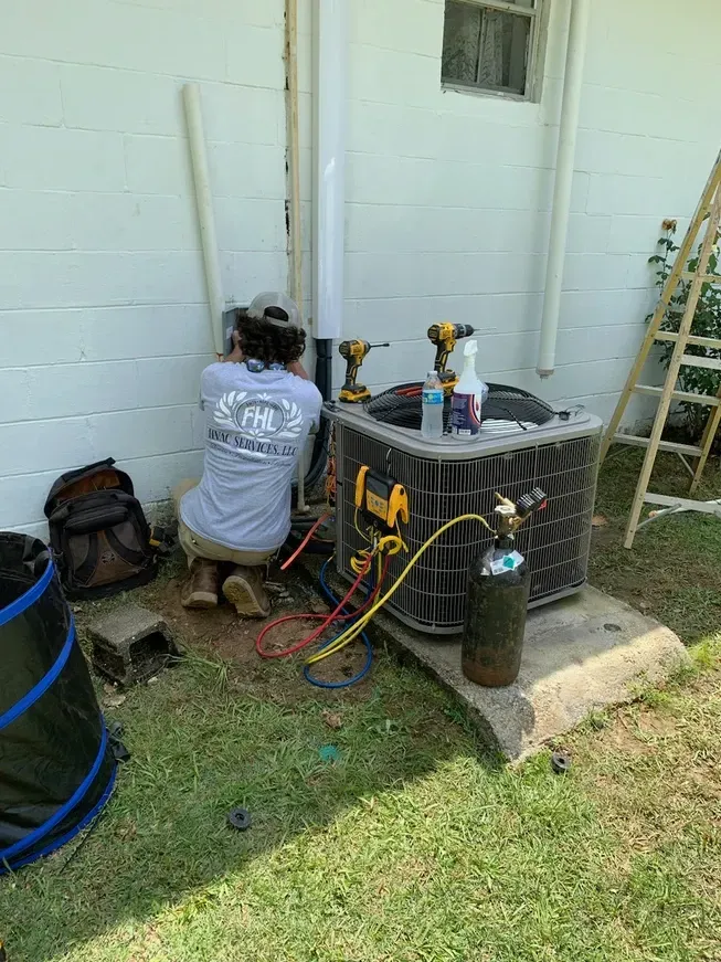 A man is working on an air conditioner outside of a house.