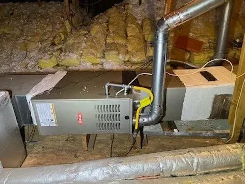 A furnace is sitting in the attic of a house.