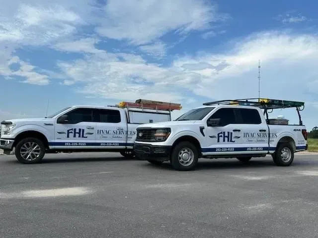 Two white trucks are parked next to each other on the side of the road.