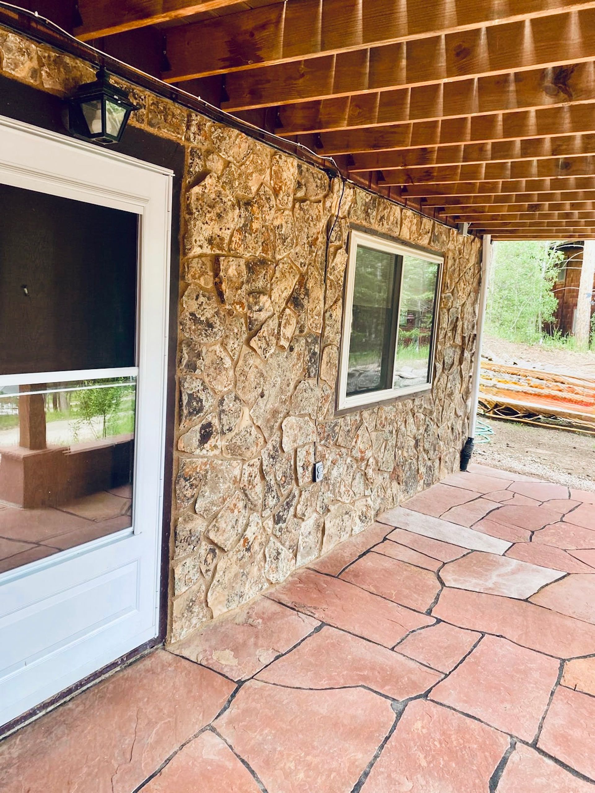 A stone wall with a white door and two windows