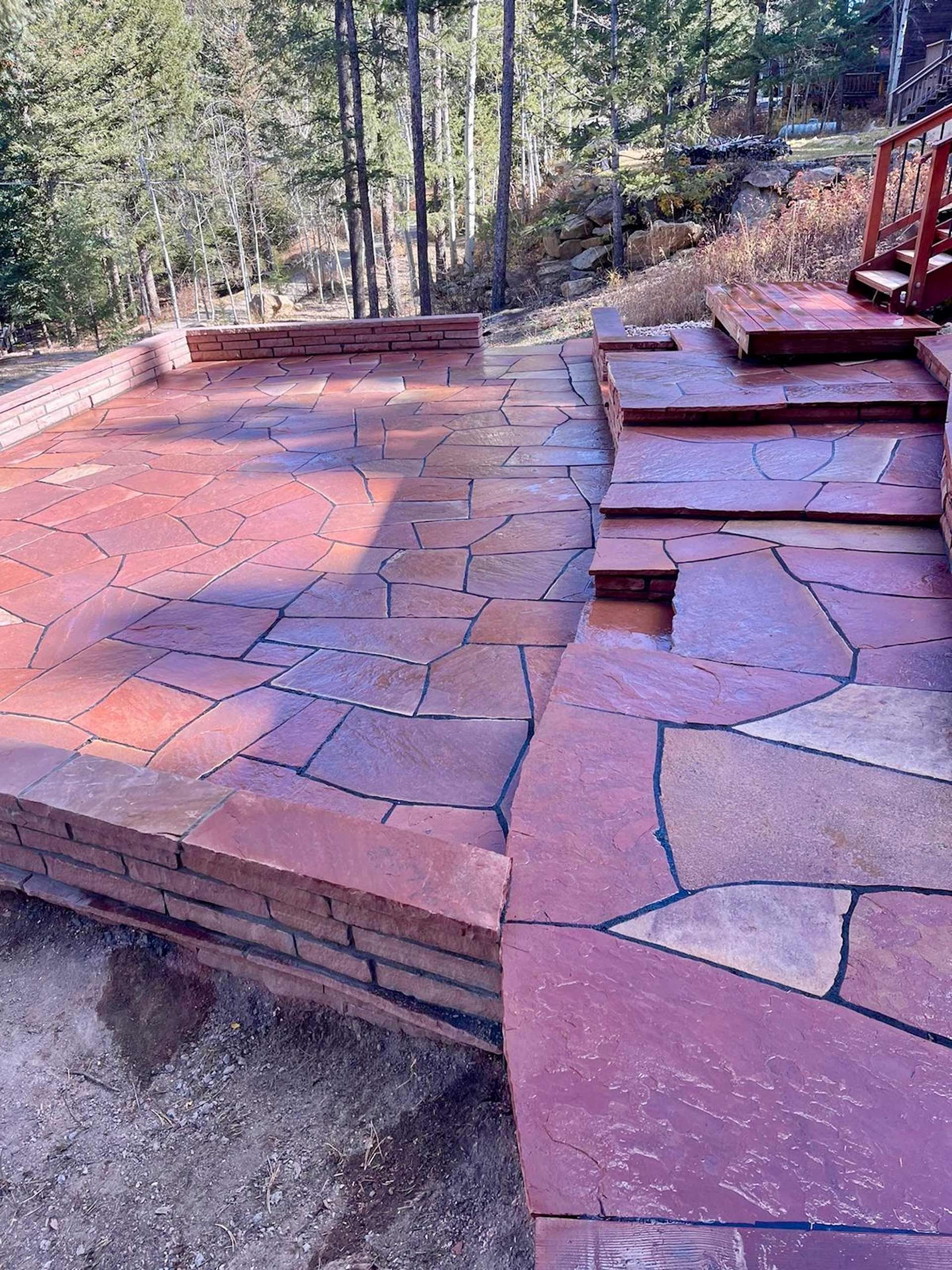 A stone walkway with stairs leading up to it in the woods.