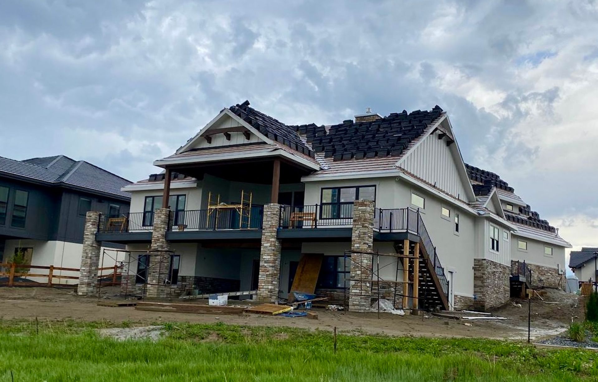 A large house under construction with a roof that has been damaged by a storm.