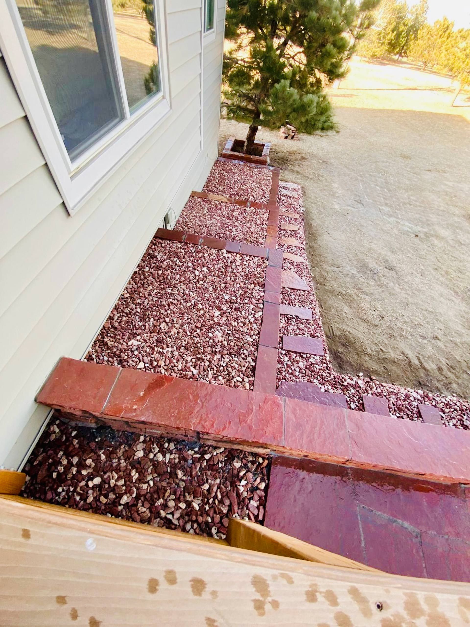 A walkway with red gravel and bricks leading to a house