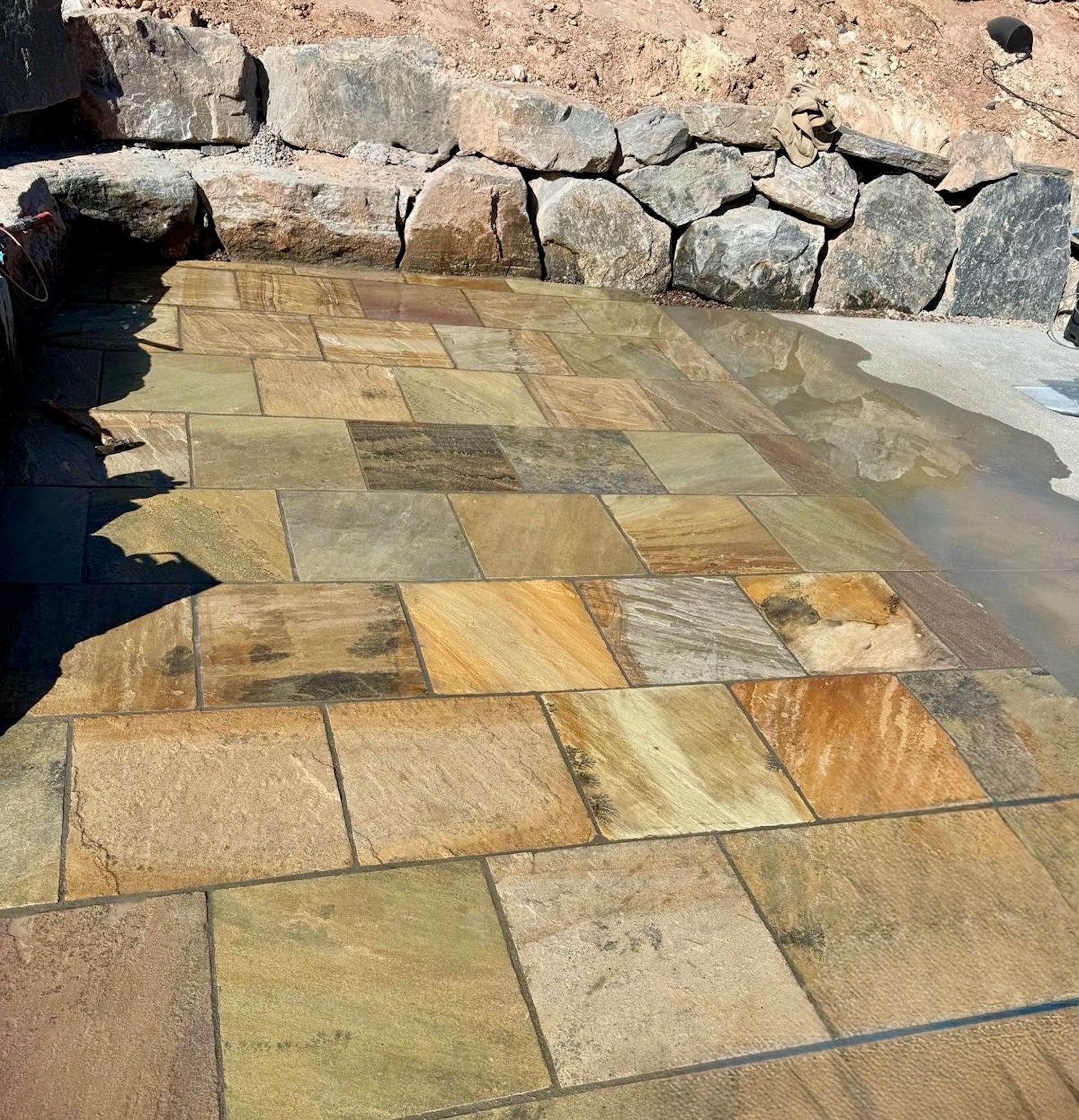 A brick walkway with a stone wall in the background