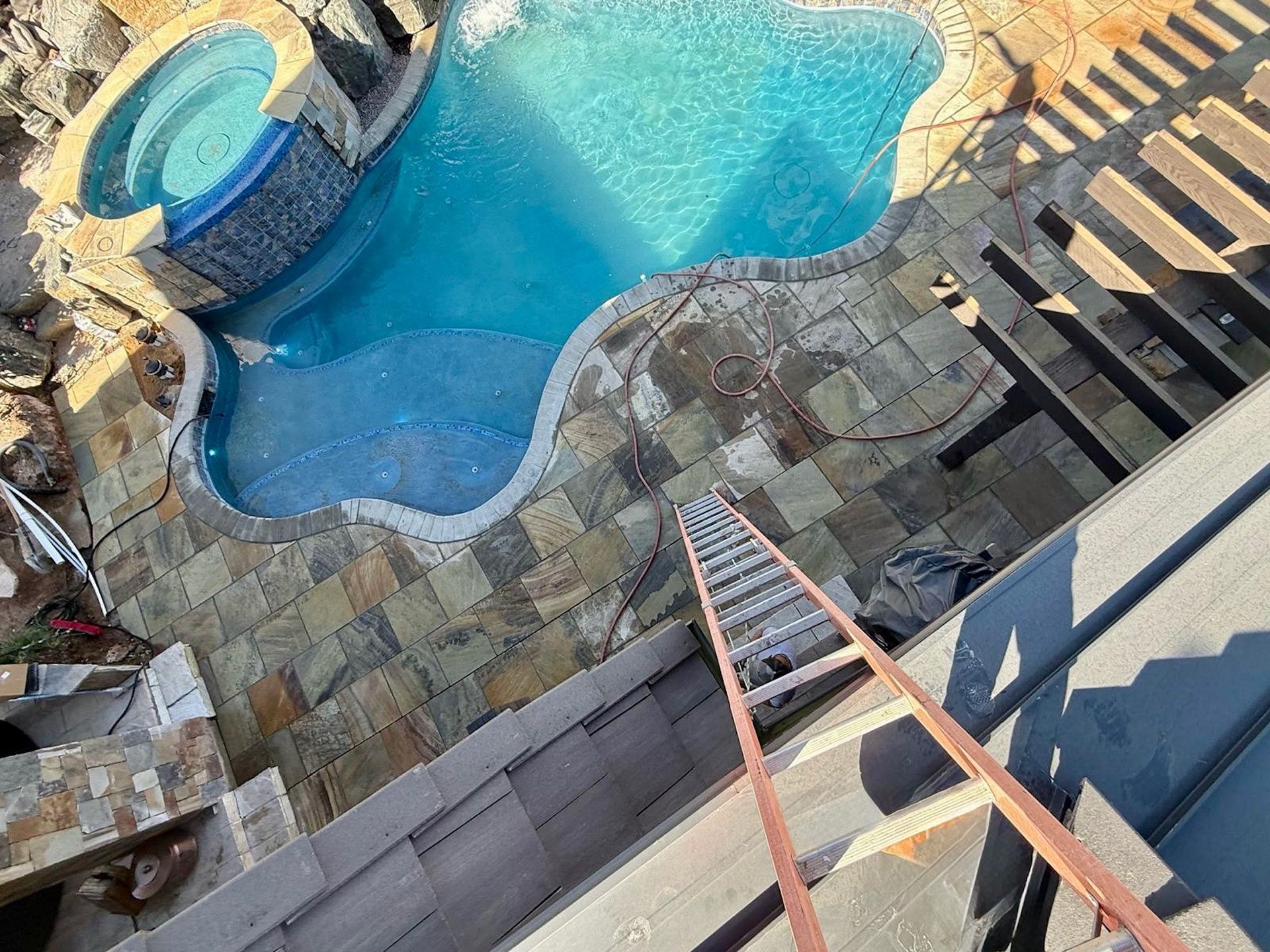 An aerial view of a swimming pool with a ladder in the foreground.