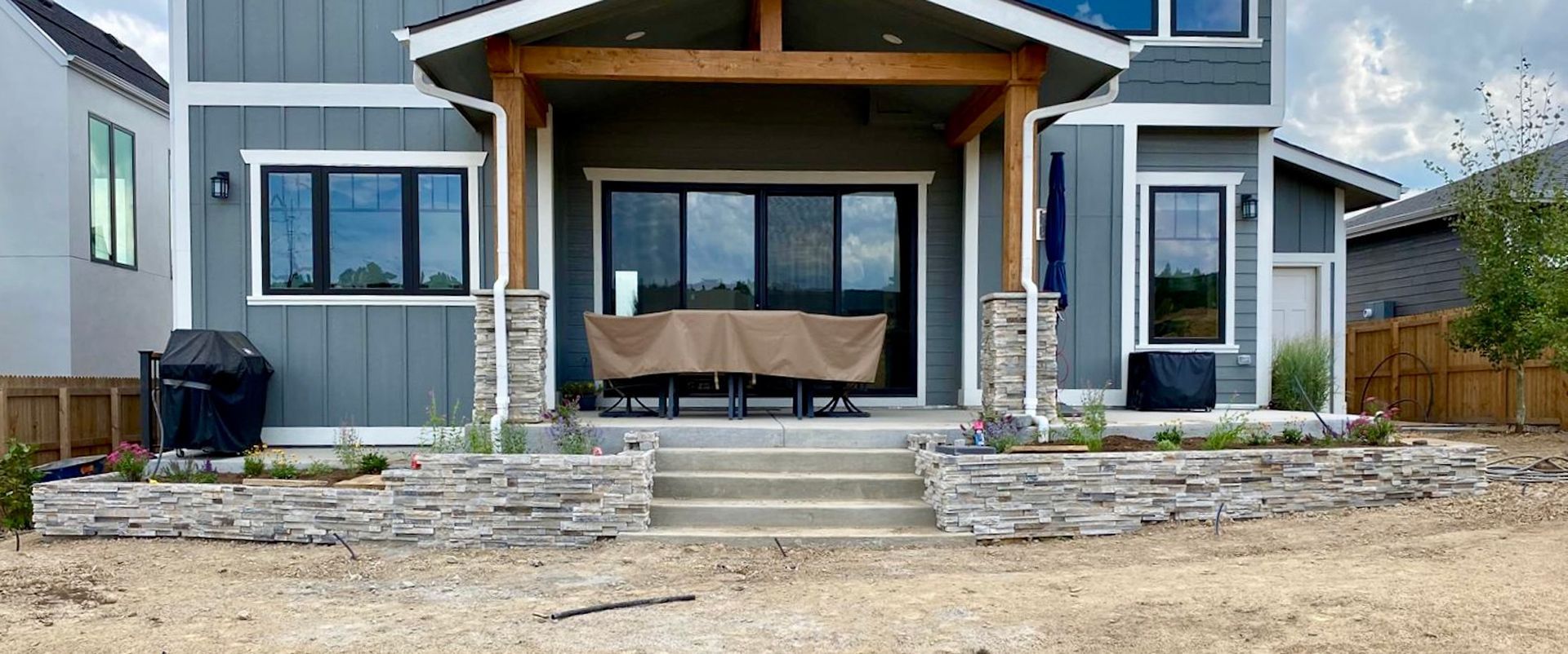 The backyard of a house with a table and chairs on the porch.