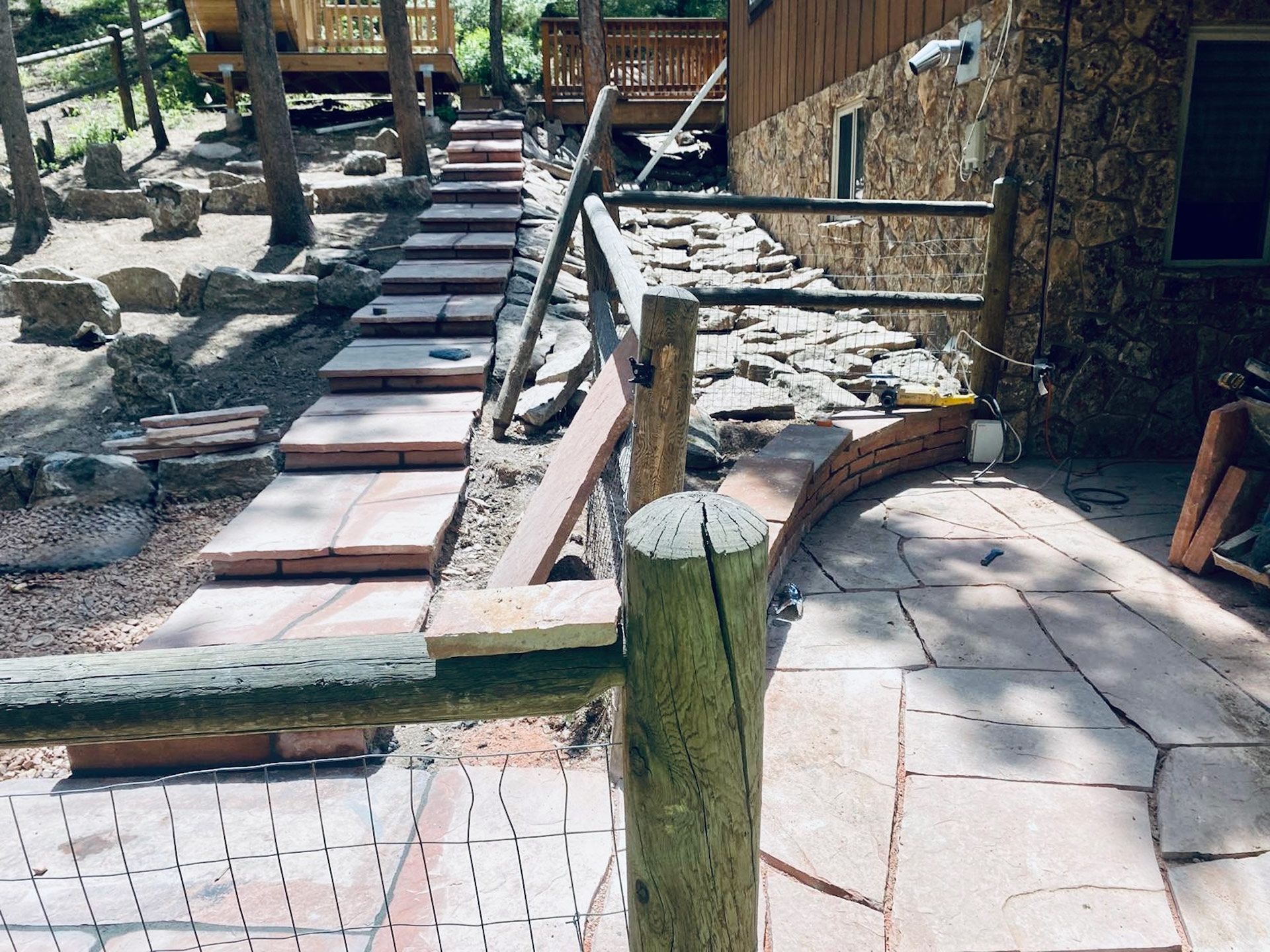 A wooden fence surrounds a brick walkway leading to a house