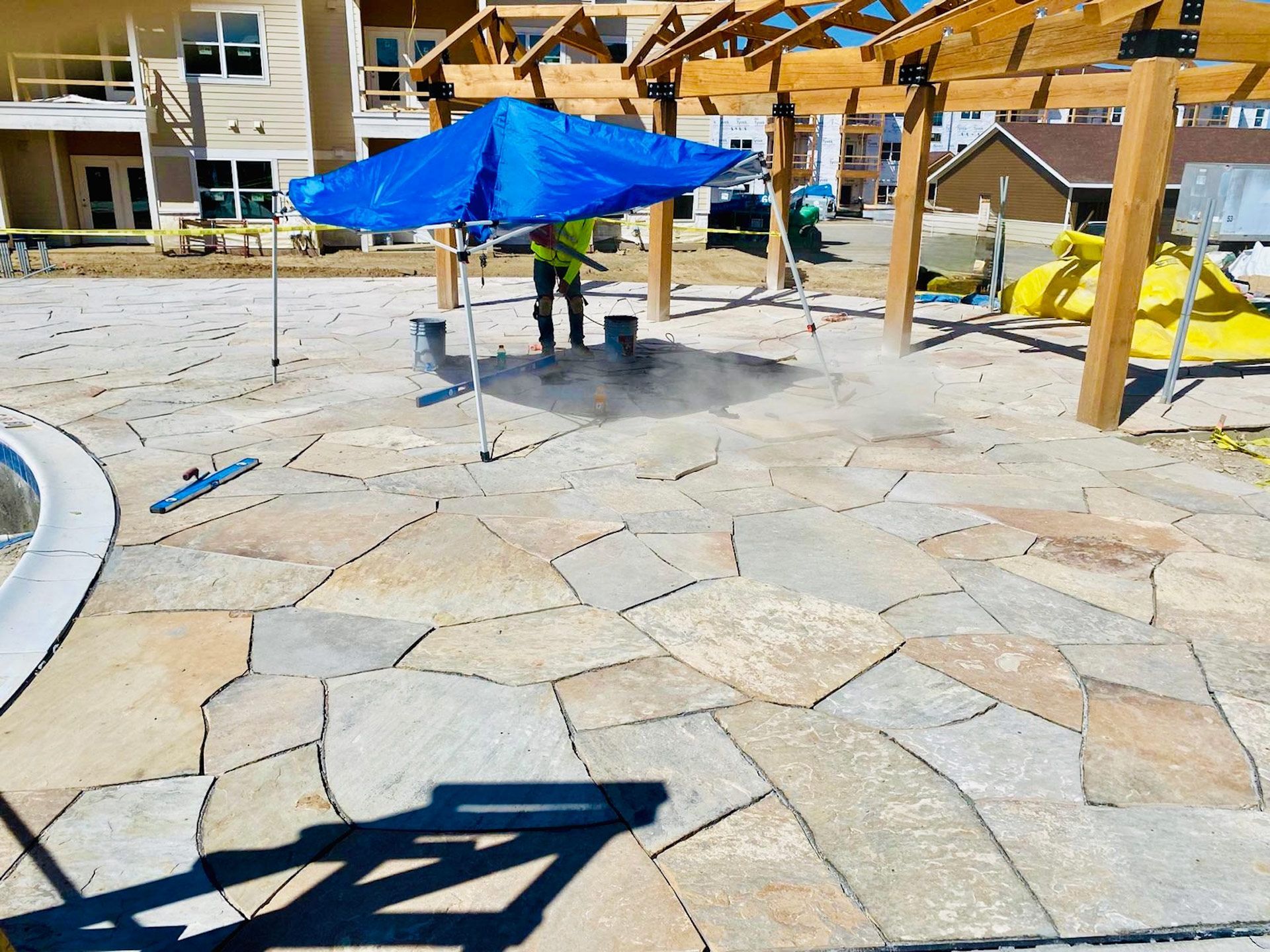 A man is standing under an umbrella on a patio