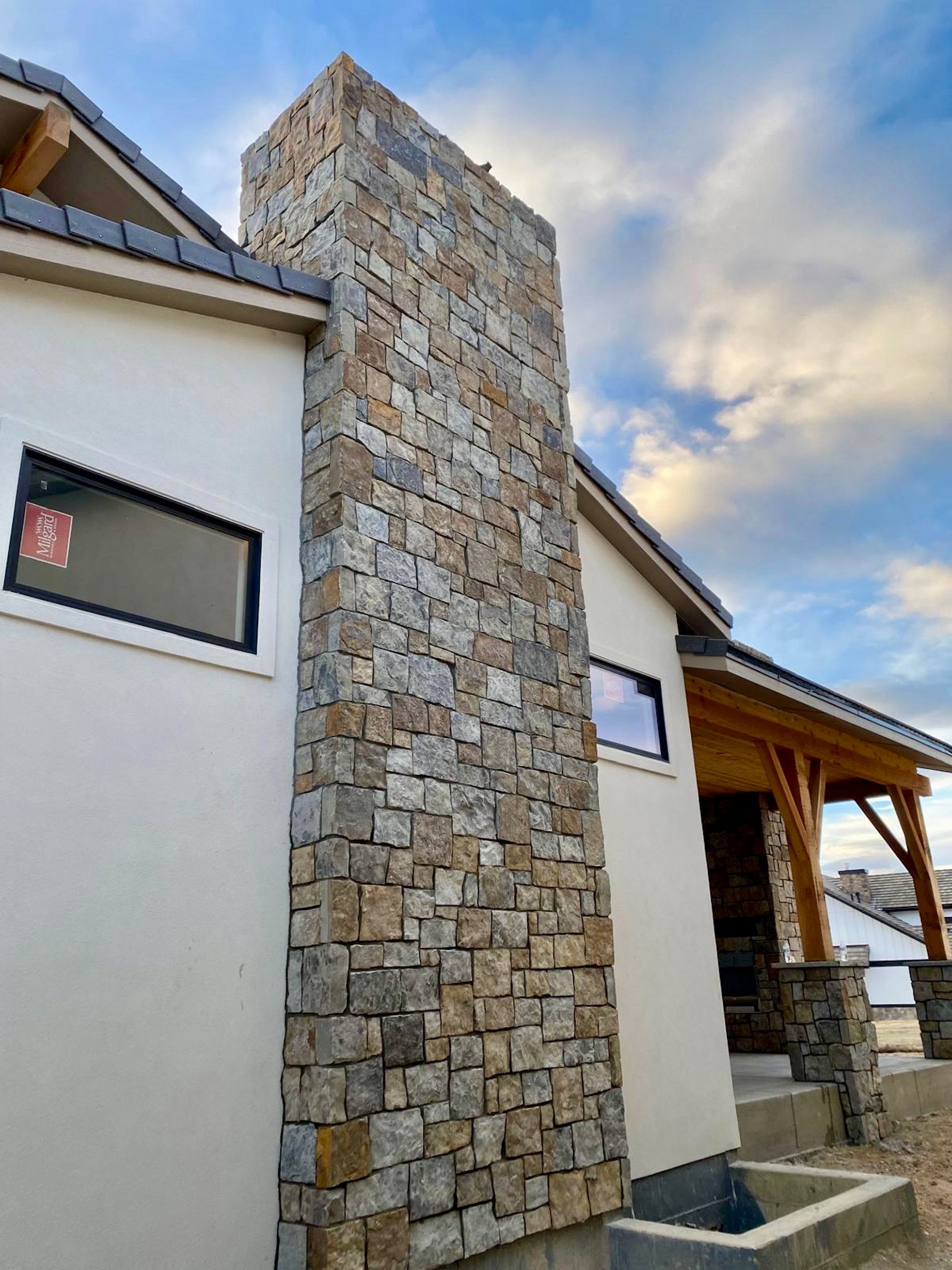 A house with a large stone chimney on the side of it.