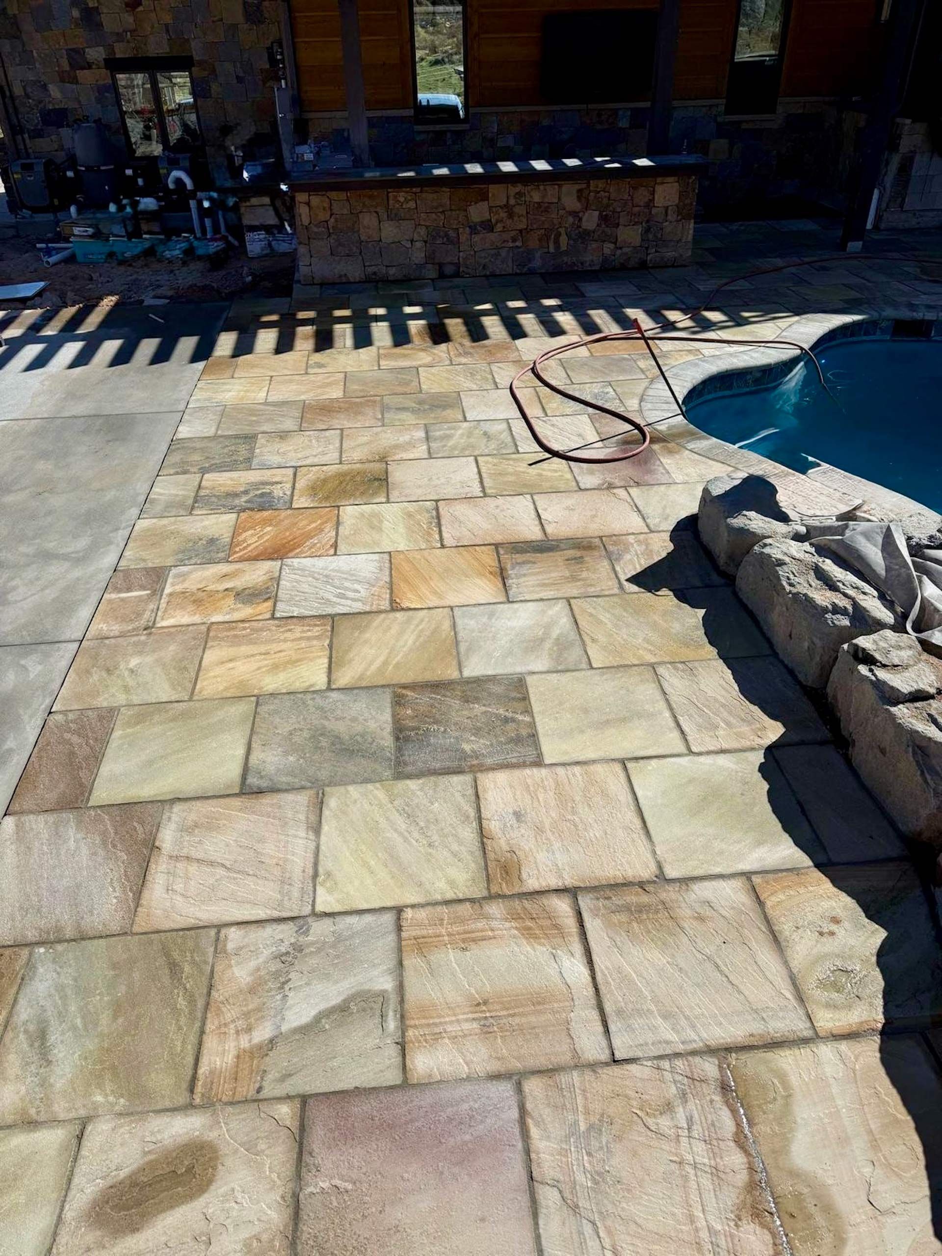 A patio with a swimming pool in the background.