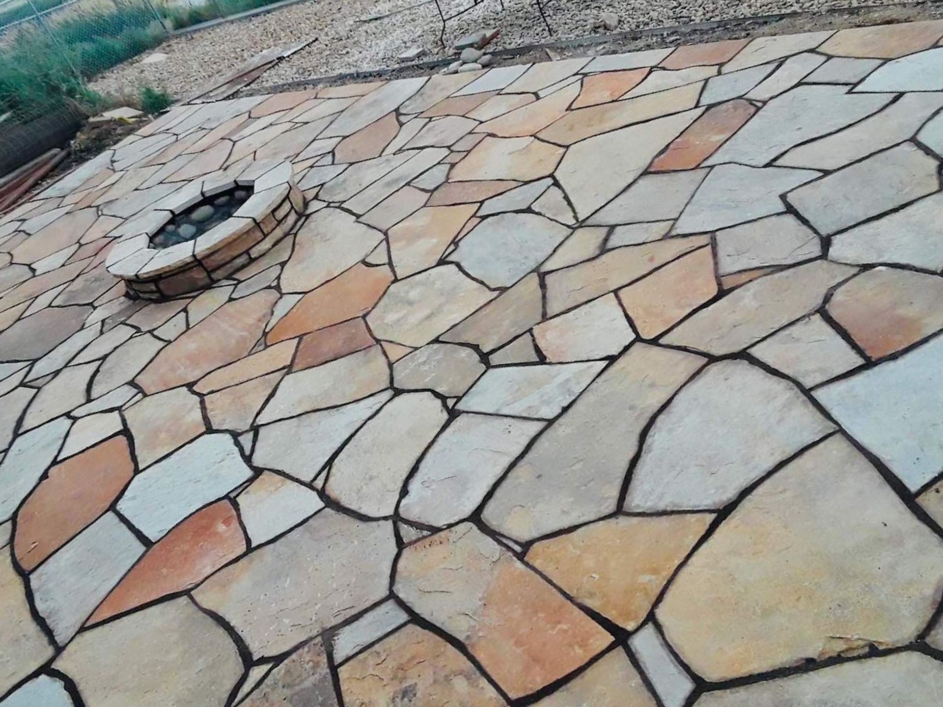 A stone patio with a fire pit in the middle