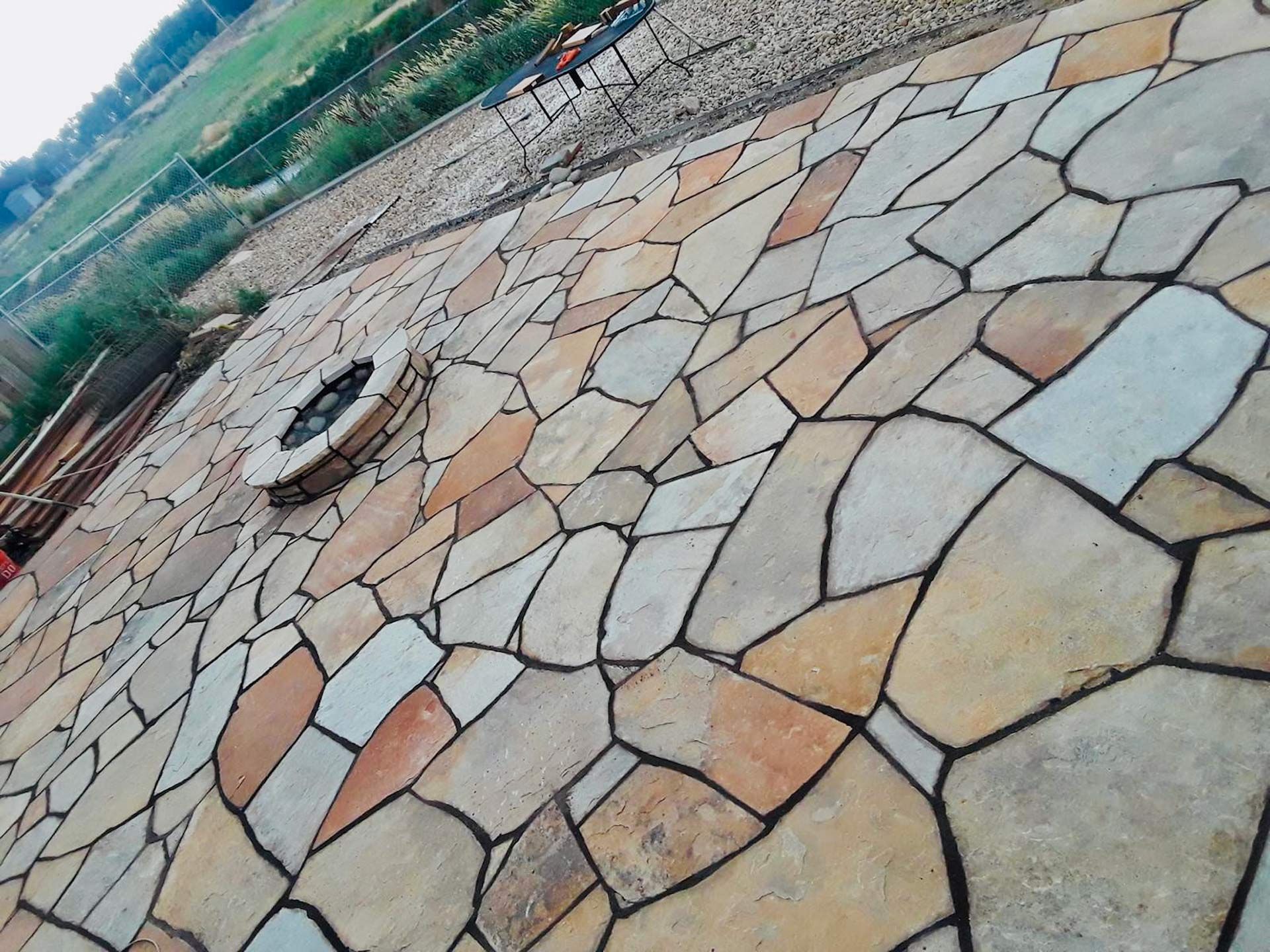 A stone patio with a fire pit in the middle