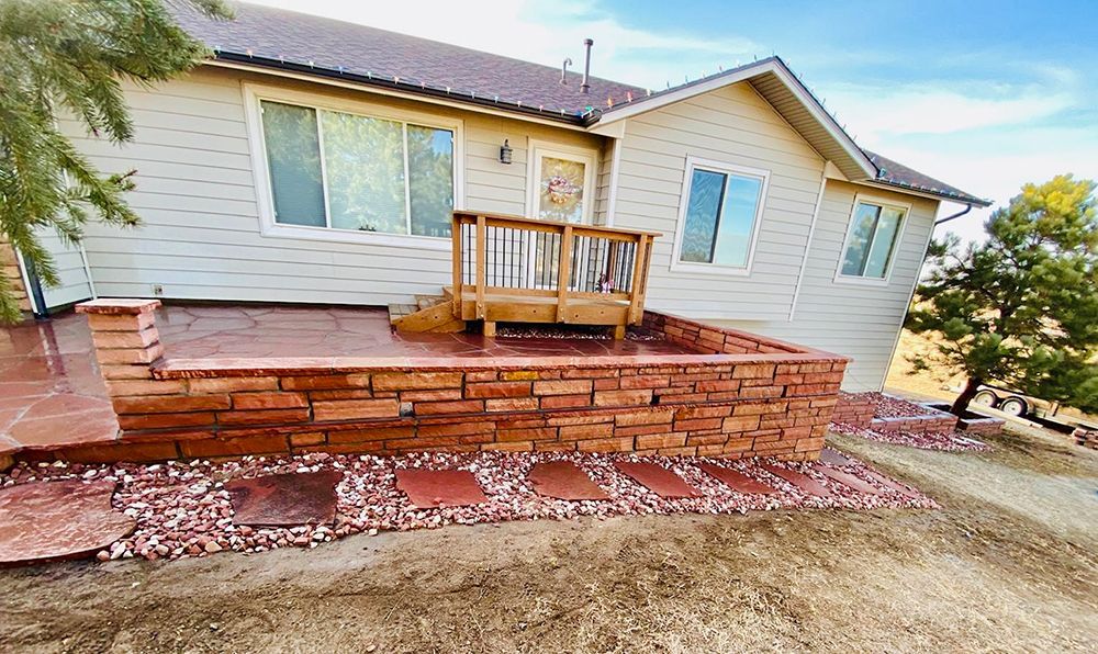 A house with a deck and a brick wall in front of it.
