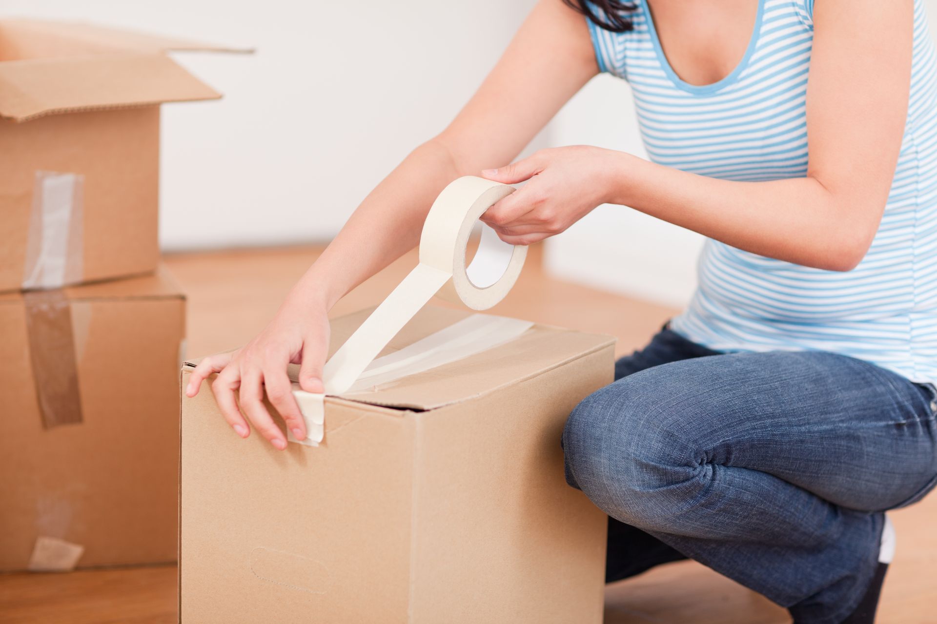 A woman is packing a box with paper tape.