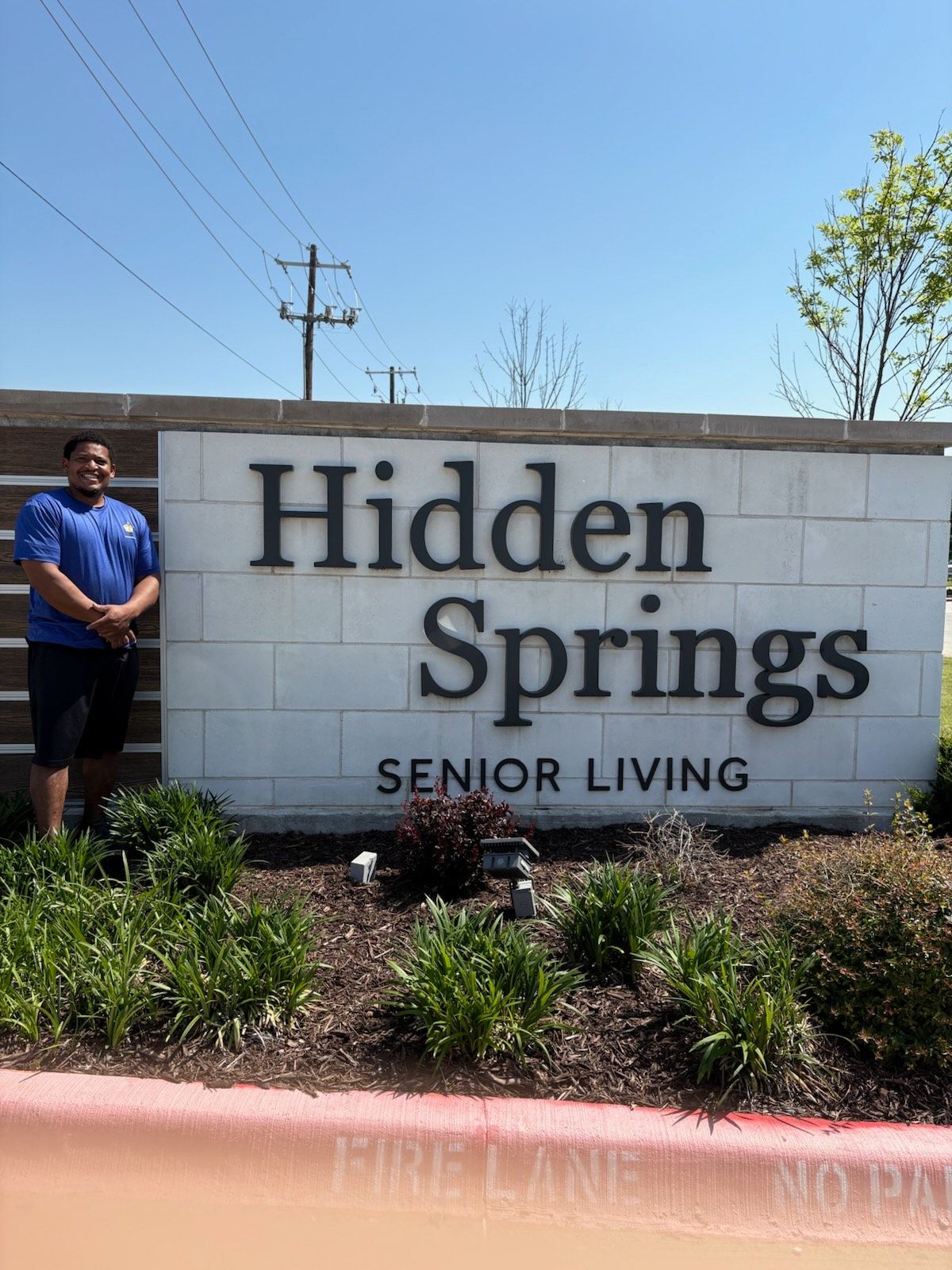 A man is standing in front of a sign for hidden springs senior living