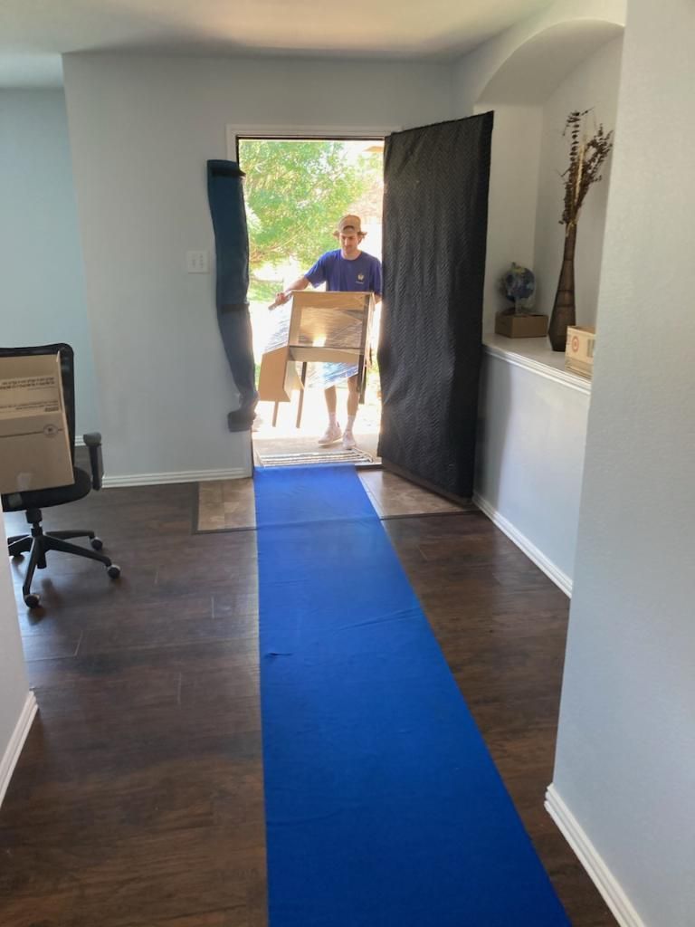 A man is carrying a box in a hallway.