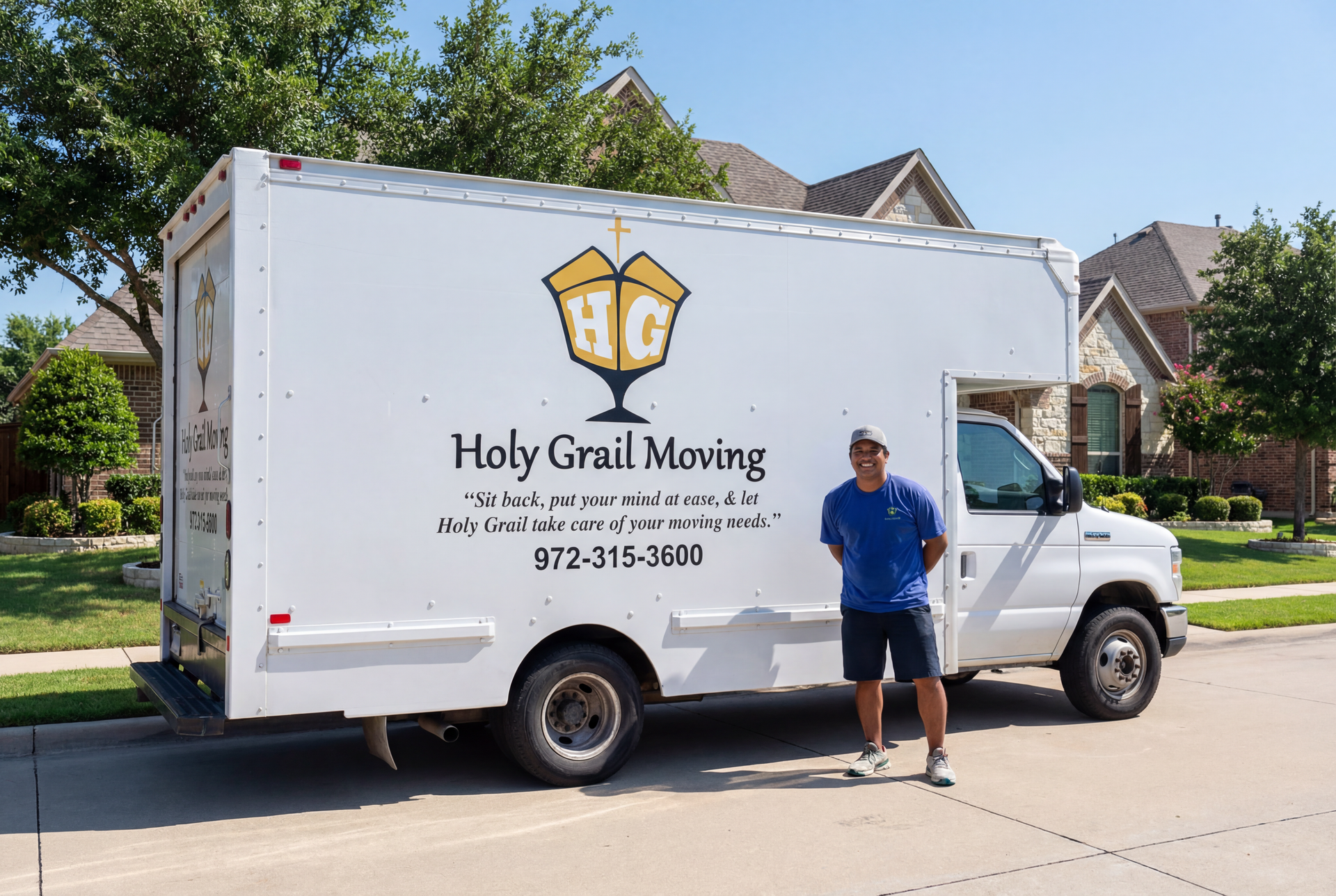 Man standing by a Holy Grail Moving truck in front of a house.