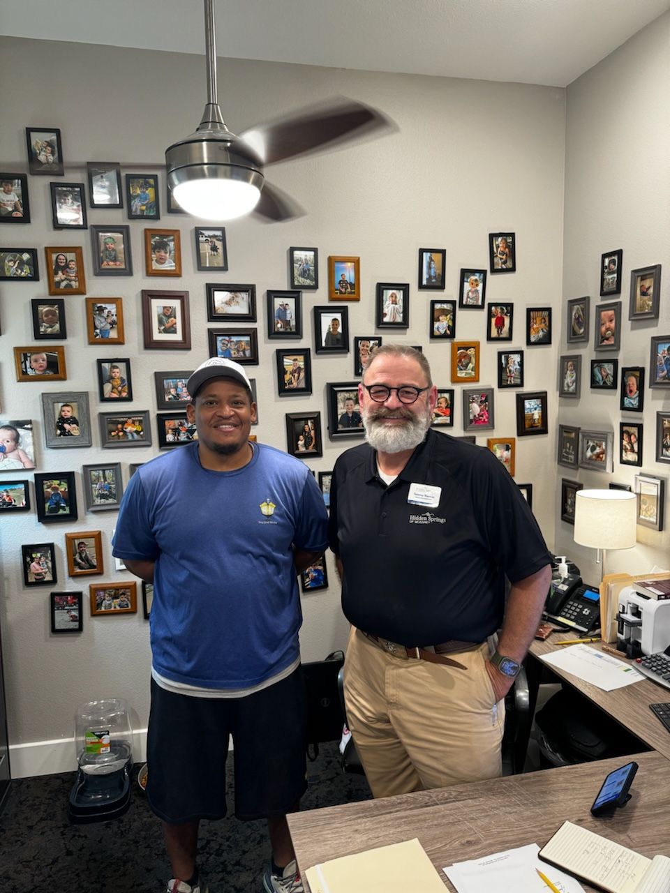Two men standing in front of a wall of pictures
