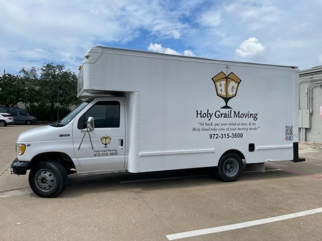 A white holy grail moving truck is parked in a parking lot