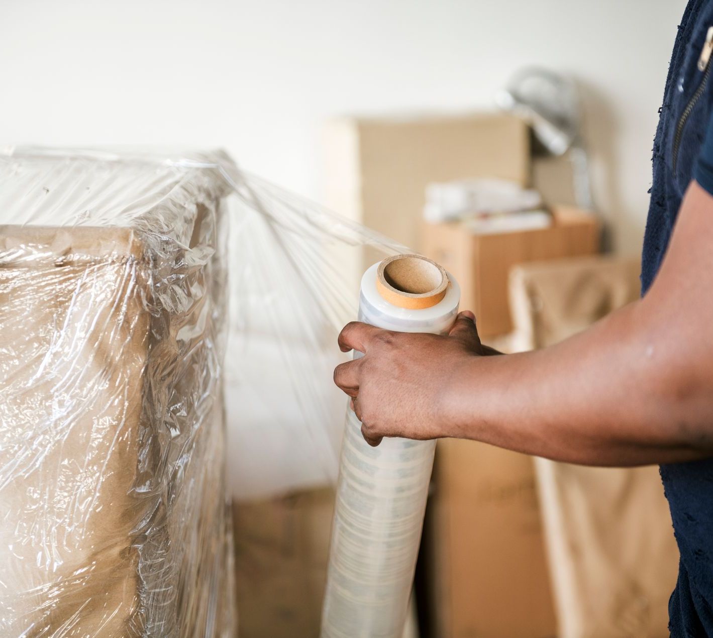 A man is wrapping a box with plastic wrap.