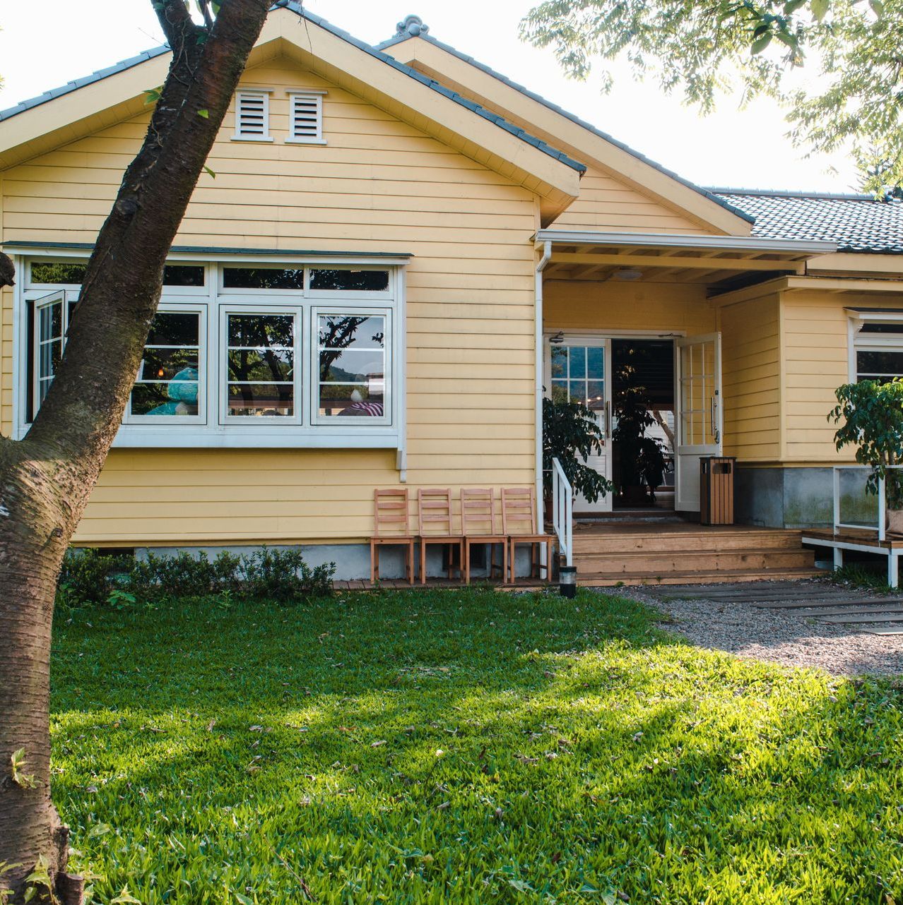 A yellow house with a tree in front of it