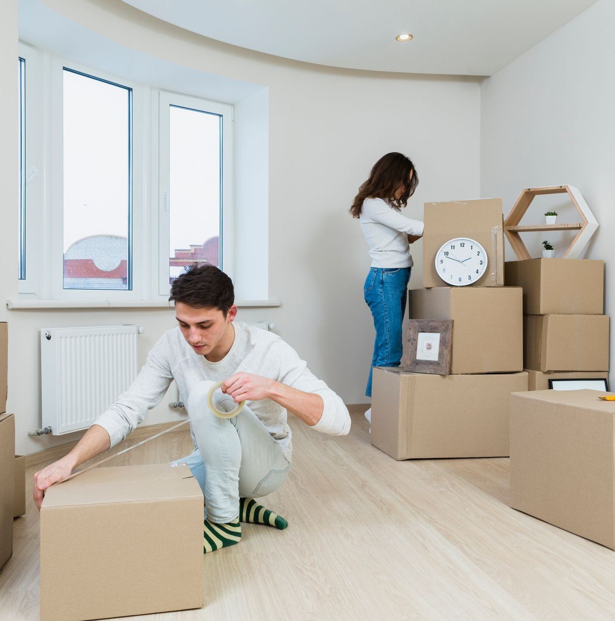 A man is kneeling down in front of a pile of cardboard boxes