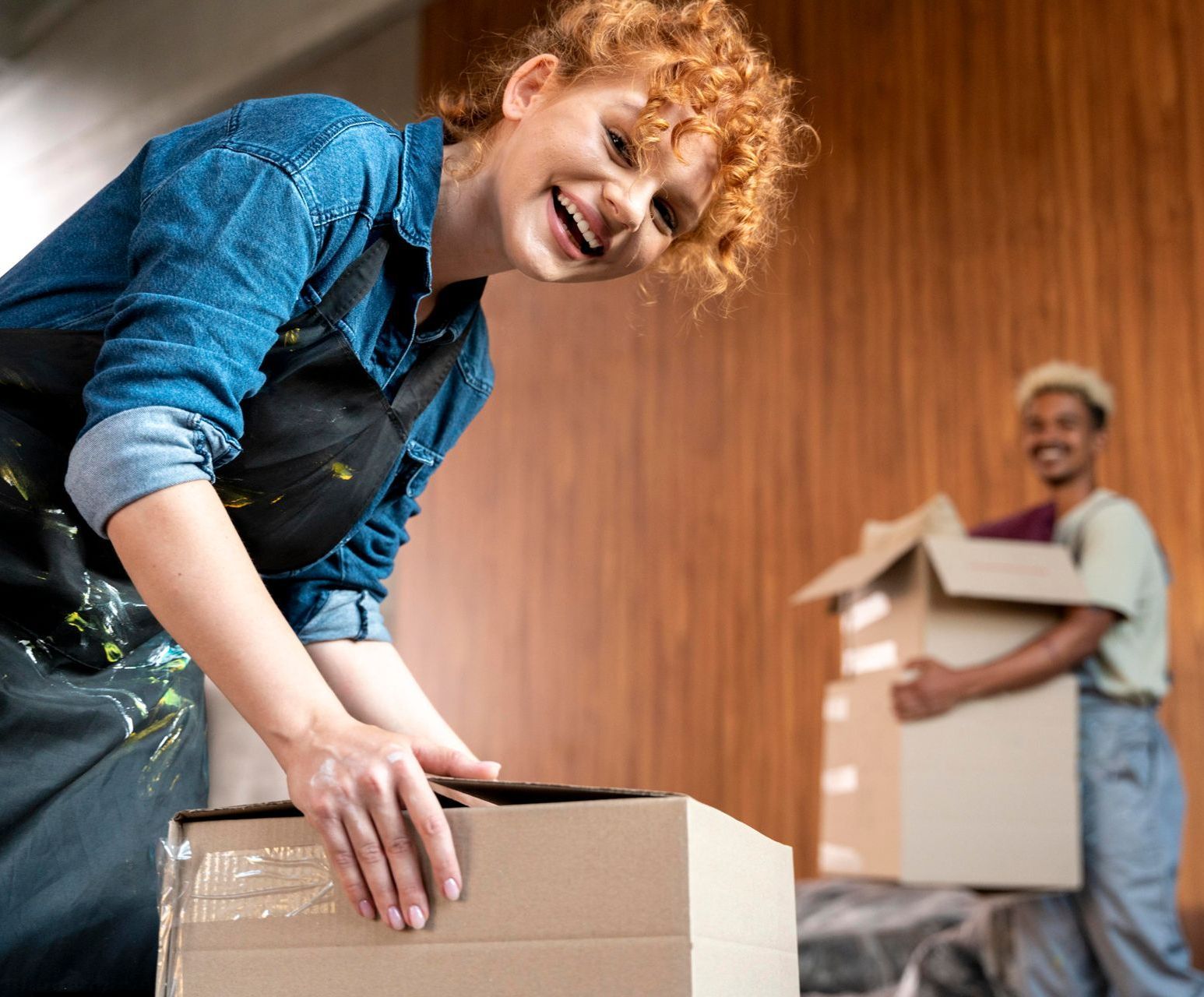 A woman is holding a cardboard box in front of a man holding a cardboard box.