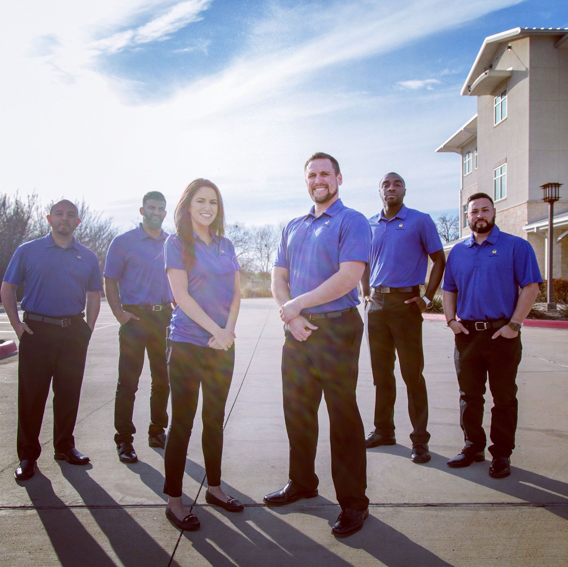A group of people in blue shirts are standing in front of a building