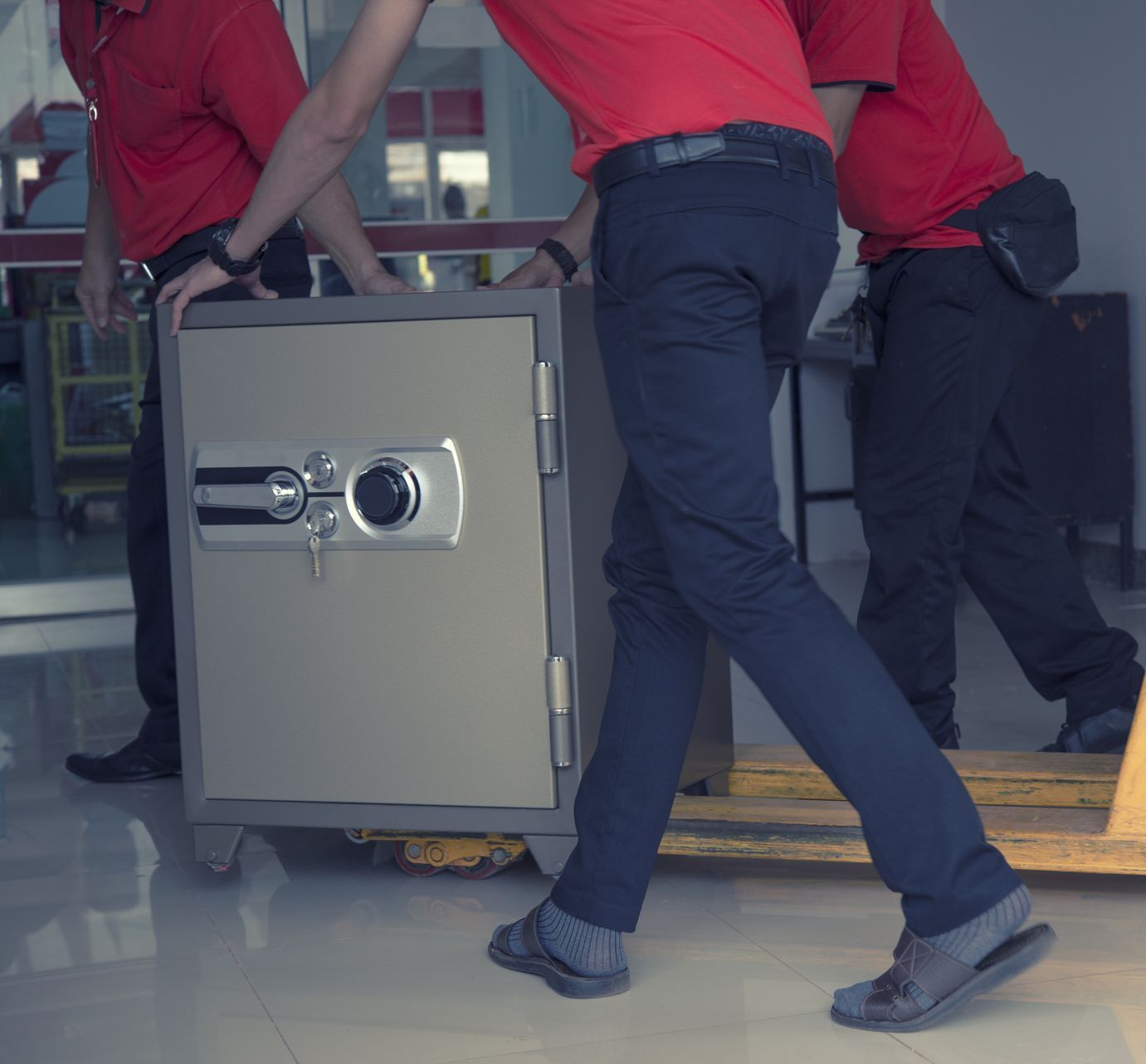 A man in a red shirt is carrying a safe