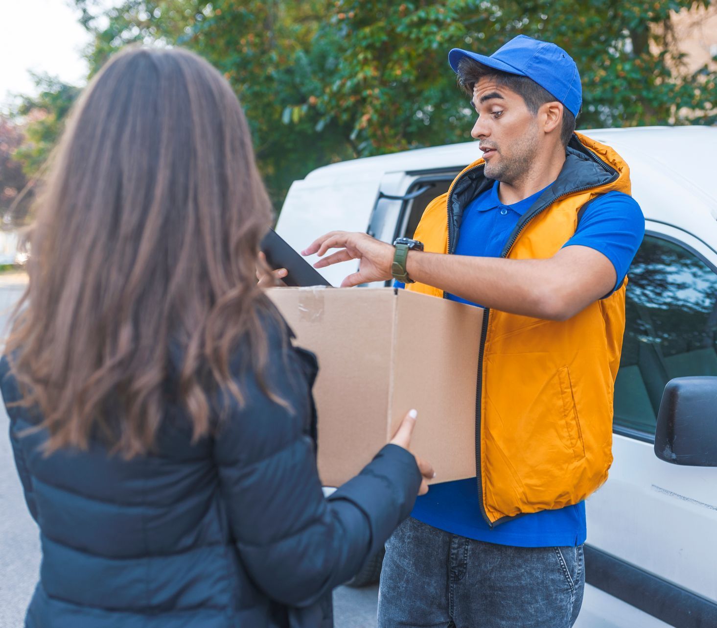 A delivery man is giving a box to a woman.