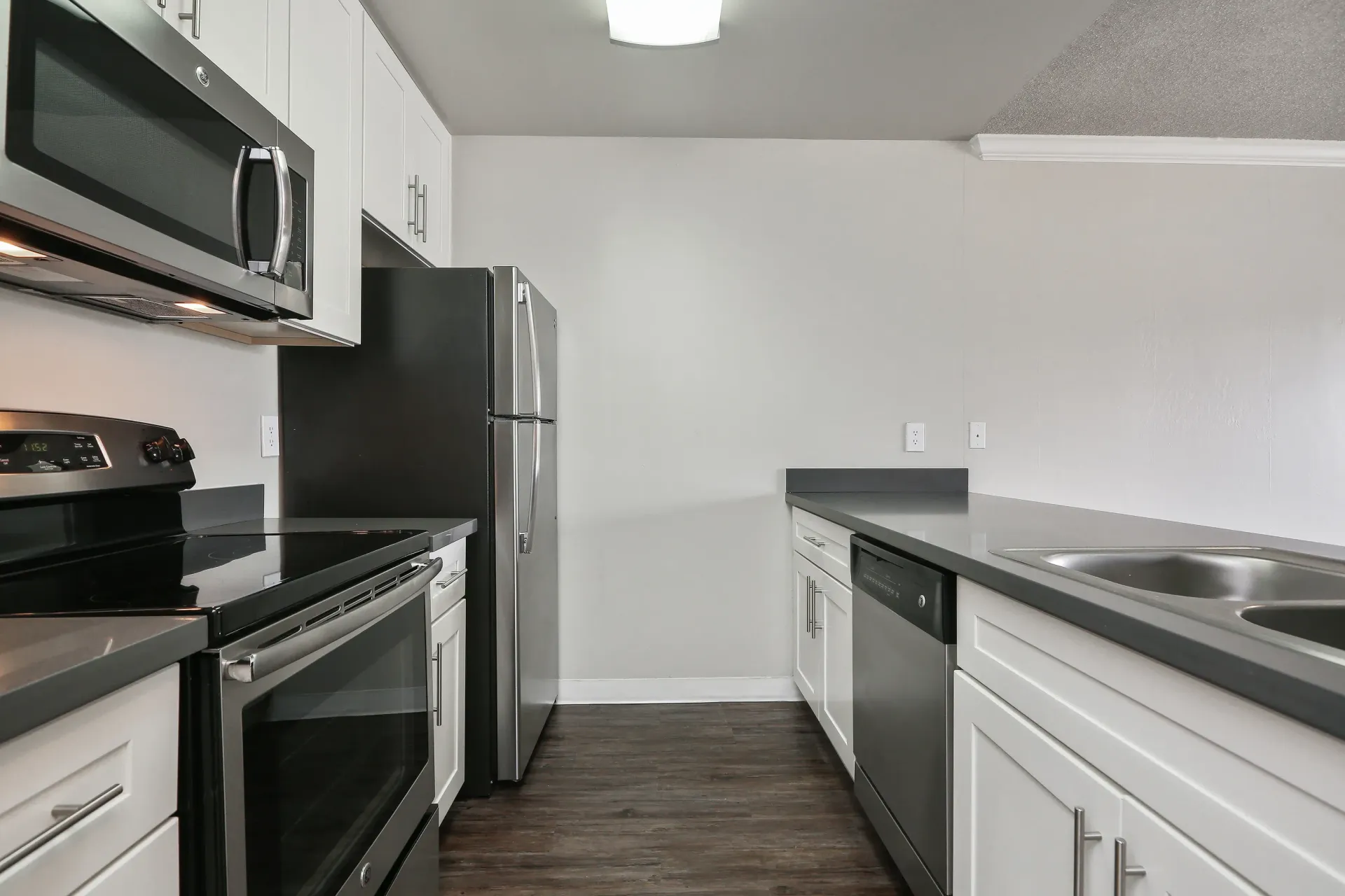 Kitchen in an apartment with stainless steel appliances, white cabinets, and gray countertops.