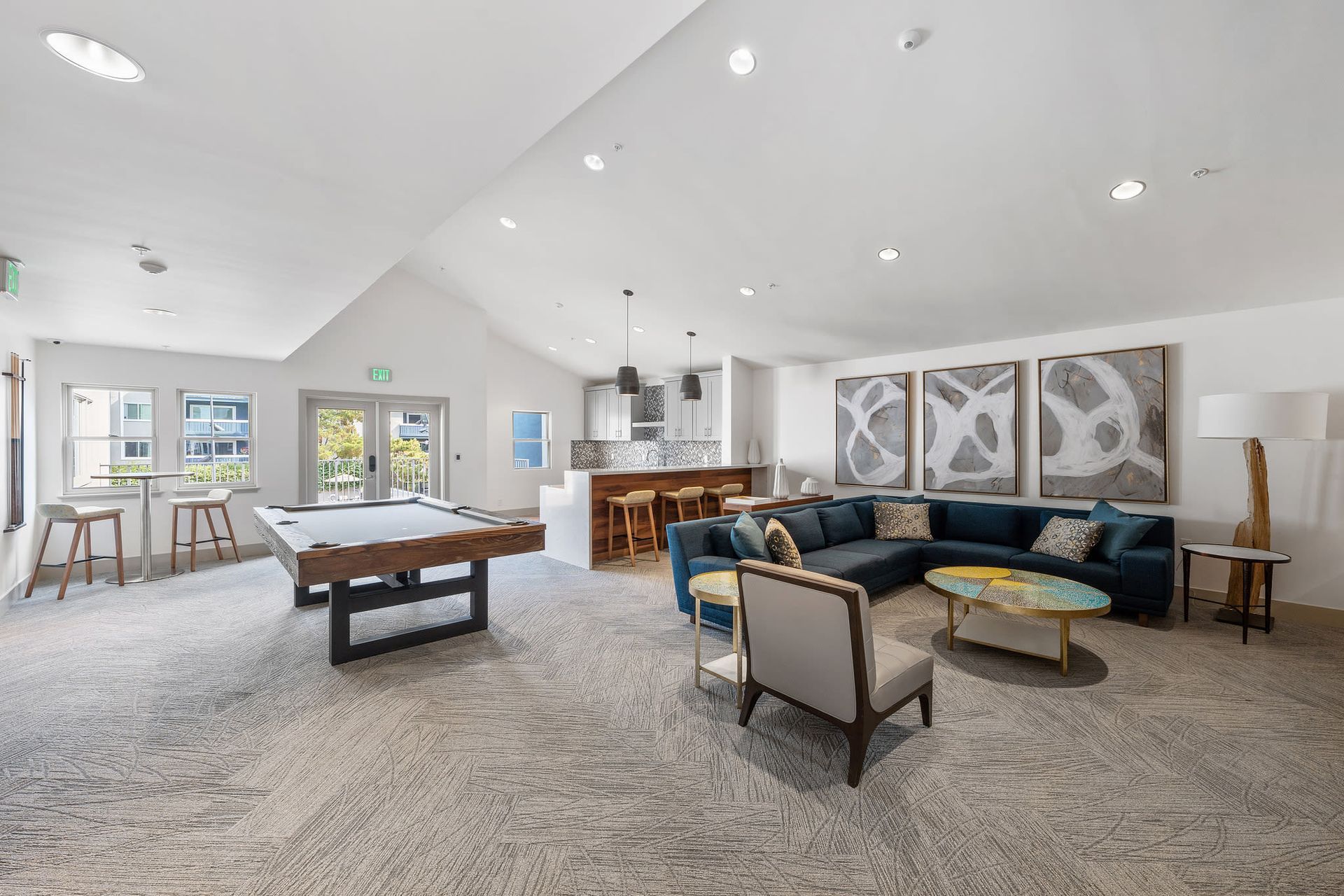 Spacious community lounge with a pool table, bar seating, and modern seating area.