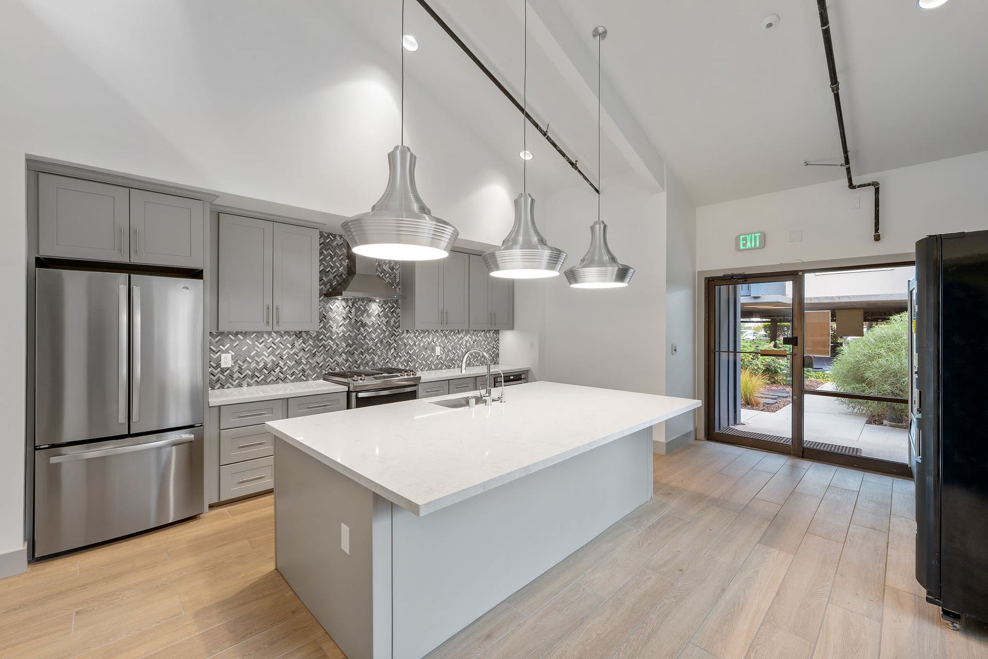 Modern apartment kitchen with a large island, stainless steel appliances, and pendant lights.