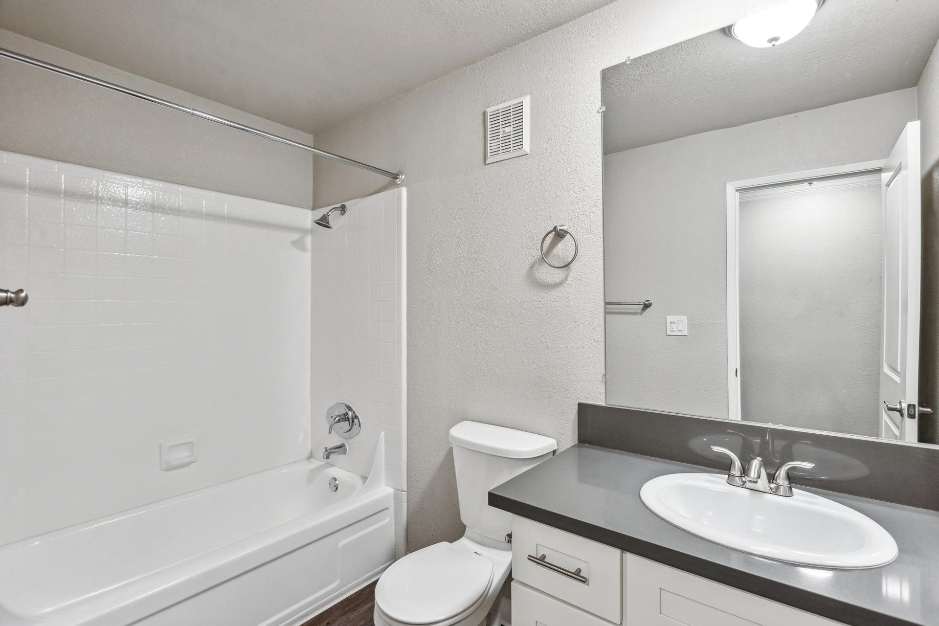 Bathroom in an apartment with a shower/tub combo, toilet, and vanity.