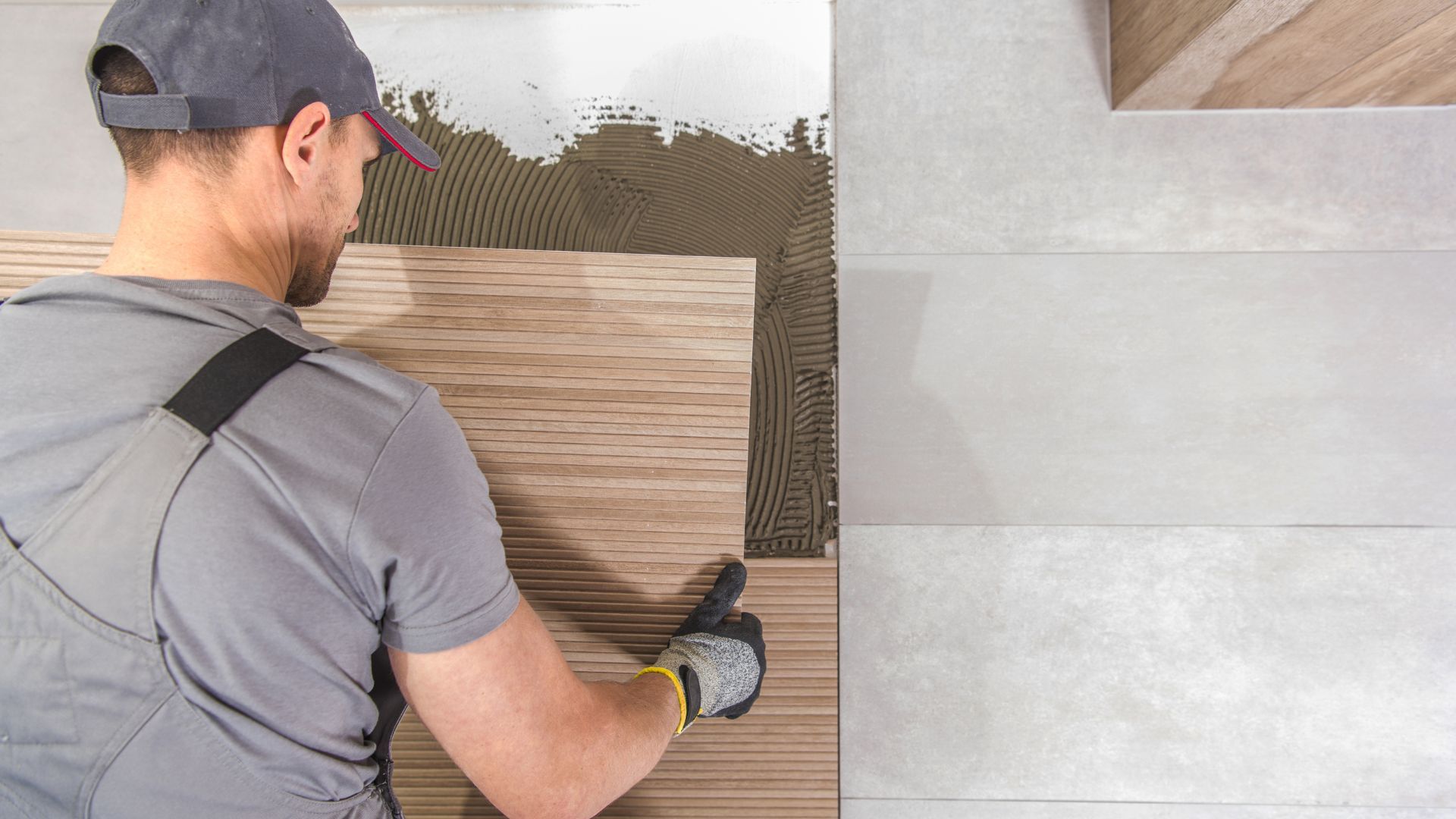 A man is laying tiles on a tiled floor.