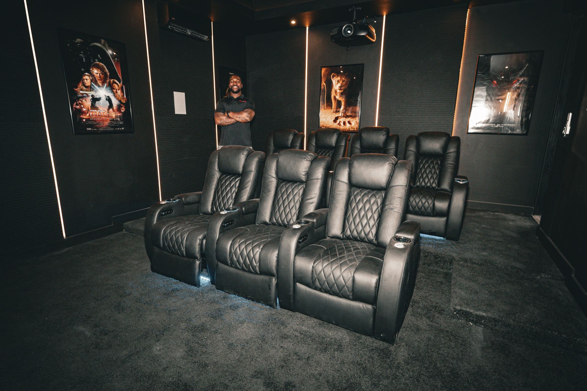 A man is standing in a home theater watching a movie.