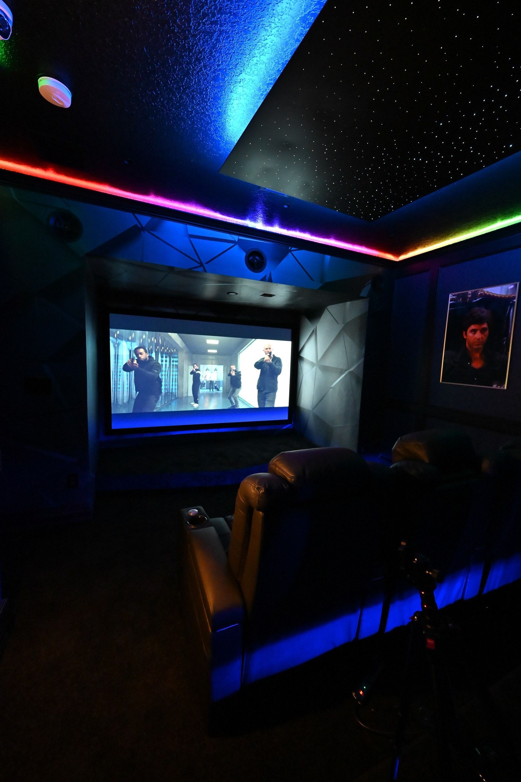 A movie theater with a projector screen and rainbow lights on the ceiling