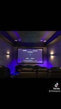A home theater with a large screen and purple lights.