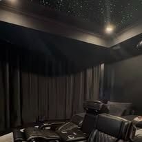A home theater with a starry sky ceiling and black curtains.