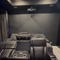 A home theater with a couch , chairs , and a projector screen.