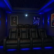 A home theater with black leather seats and blue lights.