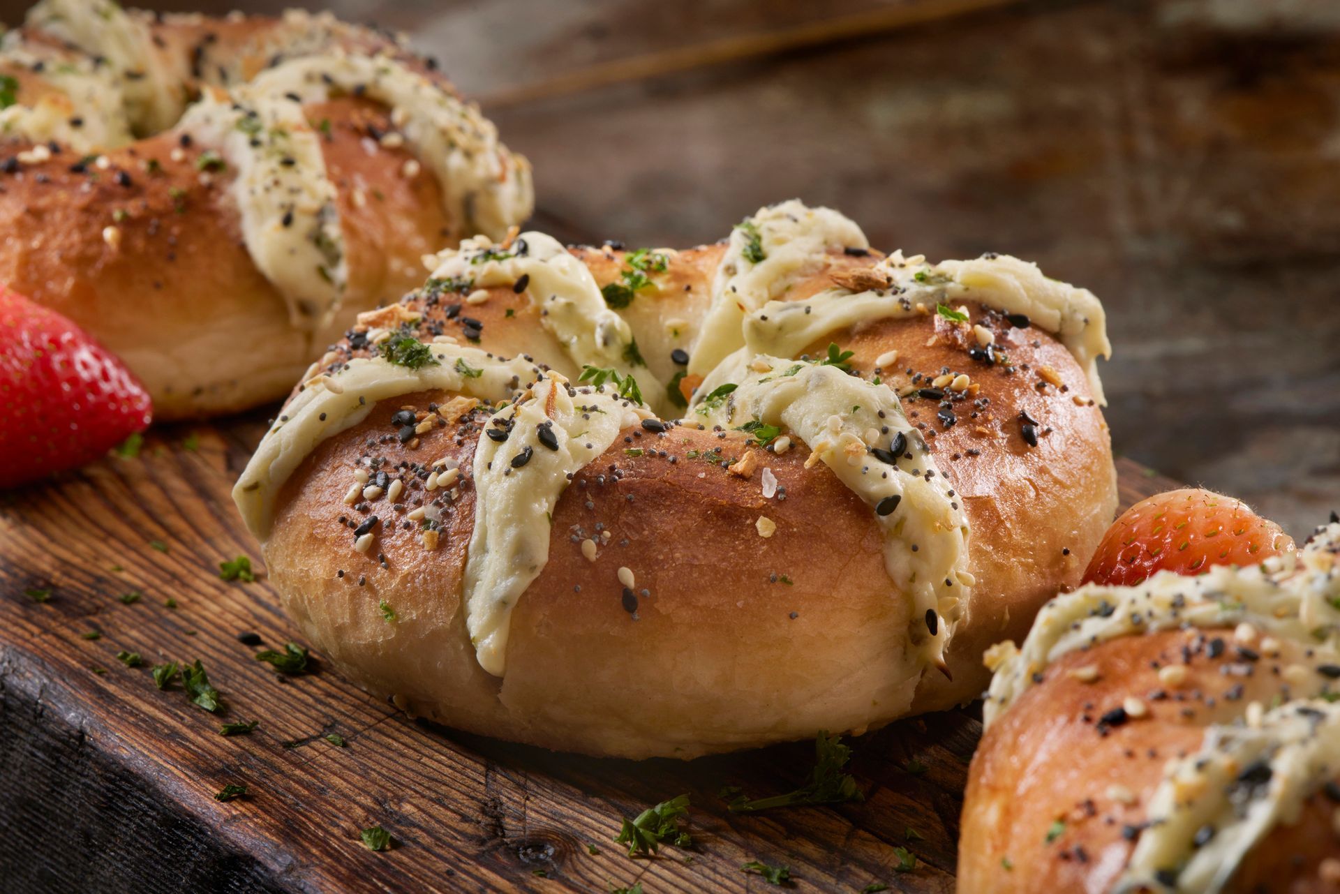 Bagels topped with cream cheese and seasonings on a wooden board.