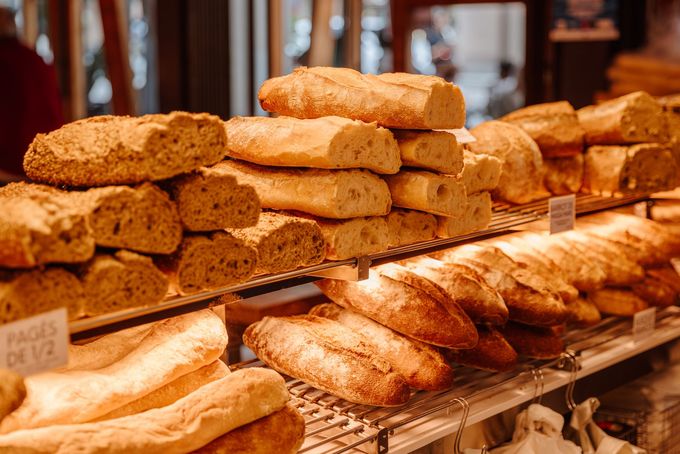 Freshly baked baguettes displayed on shelves at a bakery.
